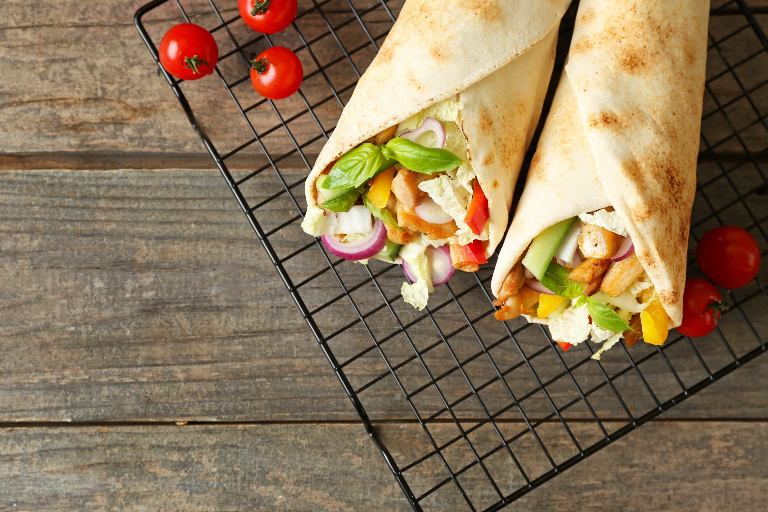 Cooling rack with tasty doner kebab on wooden table